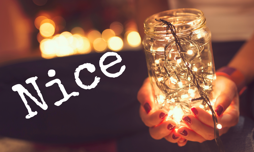 Hände halten ein beleuchtetes Einmachglas mit Lichterkette, 'Nice' Text im Vordergrund, unscharfe Lichter im Hintergrund.